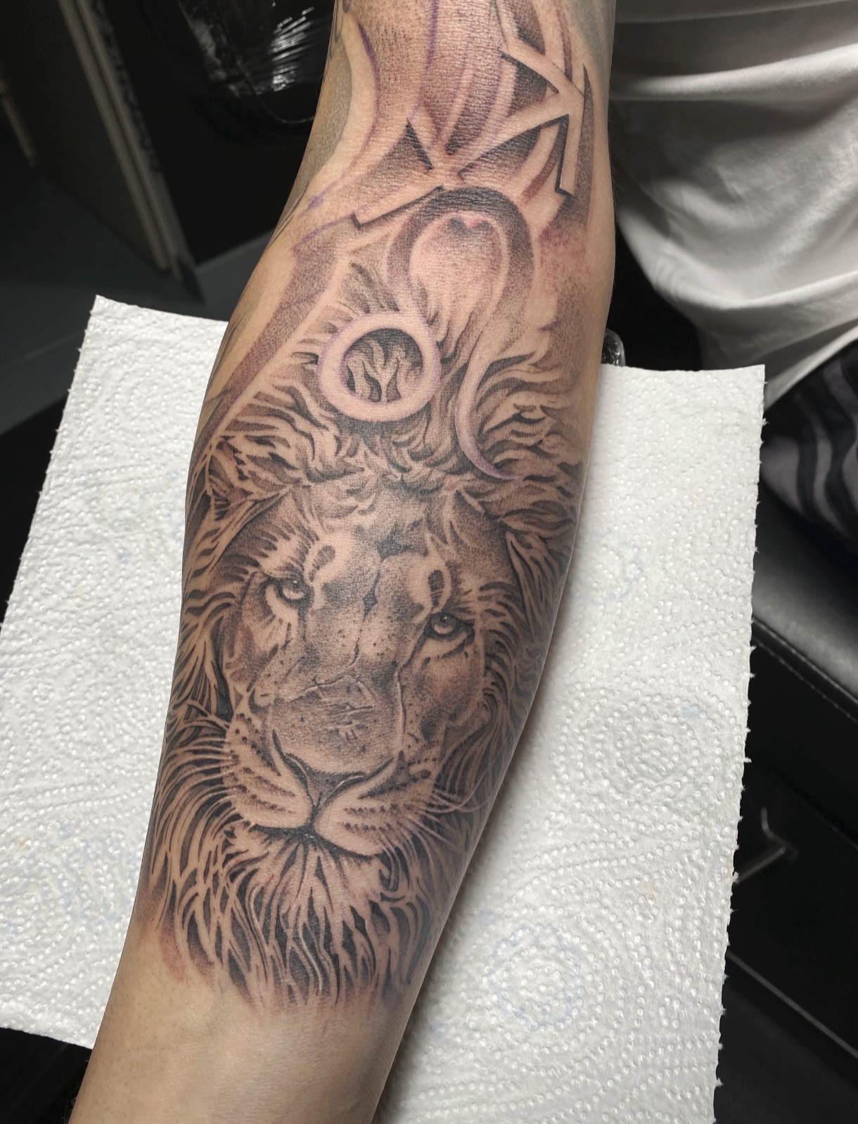 Black and grey lion tattoo with a crown